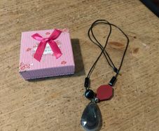 necklace featuring a striped black agate gemstone pendant and a distinct red geometric bead.