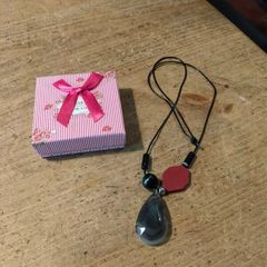 necklace featuring a striped black agate gemstone pendant and a distinct red geometric bead.