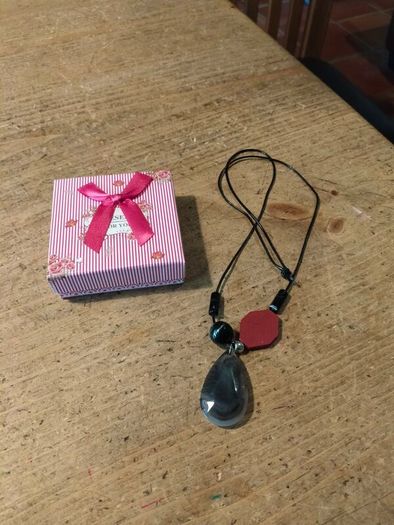 necklace featuring a striped black agate gemstone pendant and a distinct red geometric bead.