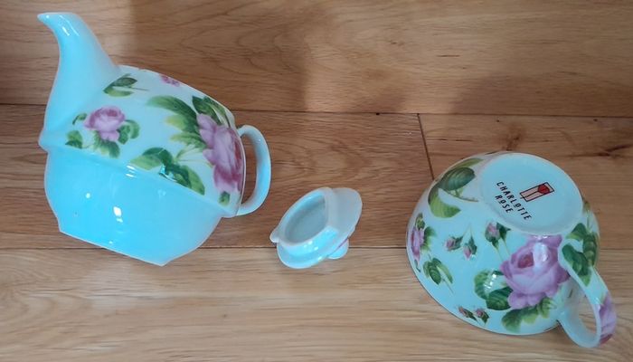 Tea for one: tea pot and cup with rose design on white