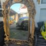 large, ornate gold mirror features a baroque frame Image 2
