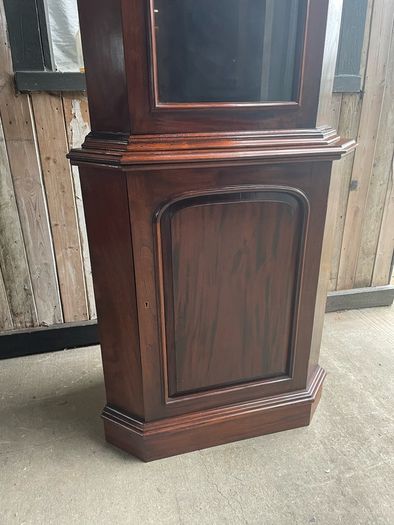 A tall mahogany corner cabinet.