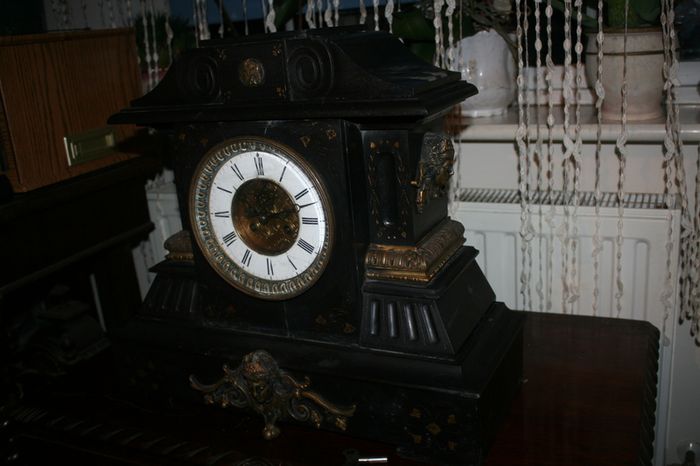Victorian French Black Slate Mantle Clock (Very large and heavy) with bronze ornamentation Oversized. Open escarpment slate plate Roman numerals. Circa 1890s. Accented with Trojan head. Flanked by two Hellenistic ladies heads on sides. Rose cartouche mask