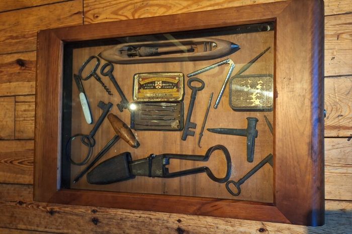 vintage shadow box containing a mix of antique tools, keys, and a loom.