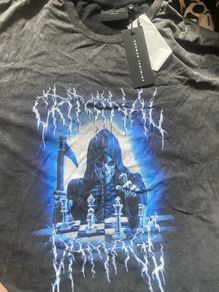 Criminal Damage Men's T-shirt Reaper Graphic Tee has a relaxed fit, short sleeves, a washed black look, and grim reaper graphics on the front.
