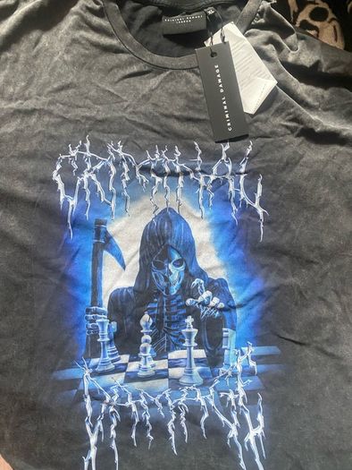 Criminal Damage Men's T-shirt Reaper Graphic Tee has a relaxed fit, short sleeves, a washed black look, and grim reaper graphics on the front.