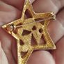 A gold star-shaped brooch. Image 3