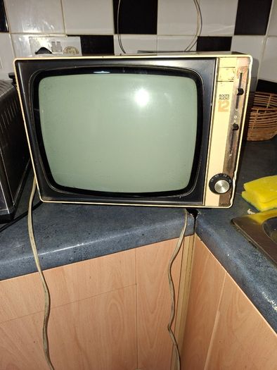 Ideal Prop, Vintage Working Boots Audio TV12 Portable Black and White CRT Television, featuring a cream plastic casing with side control dials and a 12 inch screen. Designed with dual power capabilities supporting standard mains voltage (240V) as well as 