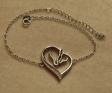 A silver bracelet with a heart-shaped pendant featuring a horse and foal's head.