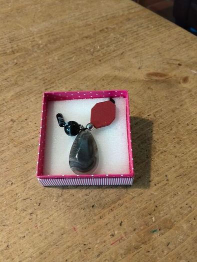 necklace featuring a striped black agate gemstone pendant and a distinct red geometric bead.