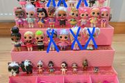 A lot of L.O.L. Surprise dolls with accessories and a doll podium.
