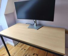 Modern desk with light wood top and black metal frame