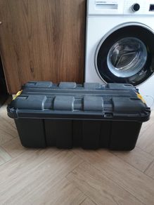 Black plastic storage trunk with lid on wheels