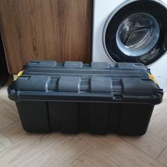 Black plastic storage trunk with lid on wheels