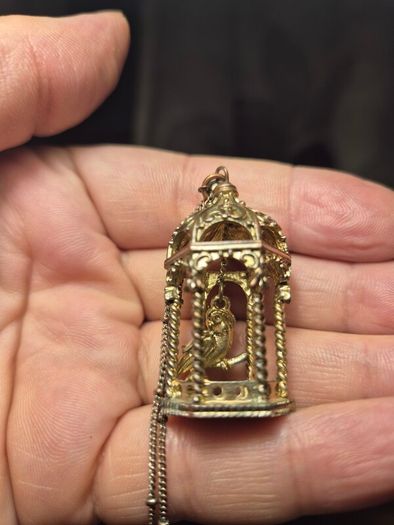 Vintage gilded bird cage with a bird pendant.