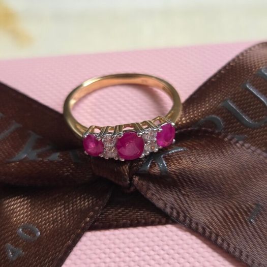 Beautiful yellow gold ring featuring three stunning rubies surrounded by sparkling cubic zirconia stones. Size M, in beautiful condition.