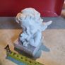 A small clay figure of an white angel on a marble plaint . Image 4