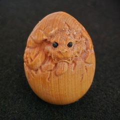 Carved wooden dragon hatching from an egg.