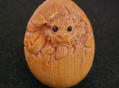 Carved wooden dragon hatching from an egg.