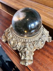 Vintage Crystal ball resting on an ornate, cast metal pedestal