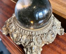 Vintage Crystal ball resting on an ornate, cast metal pedestal