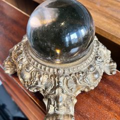 Vintage Crystal ball resting on an ornate, cast metal pedestal