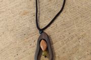 wooden pendant necklace featuring a dark brown wooden frame, a light-colored central bead, and a small dark yellow stone accent on an adjustable braided cord.