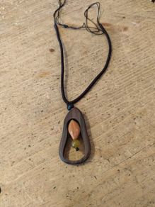 wooden pendant necklace featuring a dark brown wooden frame, a light-colored central bead, and a small dark yellow stone accent on an adjustable braided cord.