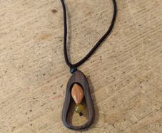 wooden pendant necklace featuring a dark brown wooden frame, a light-colored central bead, and a small dark yellow stone accent on an adjustable braided cord.