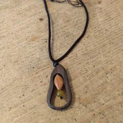 wooden pendant necklace featuring a dark brown wooden frame, a light-colored central bead, and a small dark yellow stone accent on an adjustable braided cord.