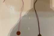 Rituals red/pink string bracelet with round Rituals engraved charm