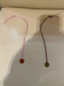 Rituals red/pink string bracelet with round Rituals engraved charm