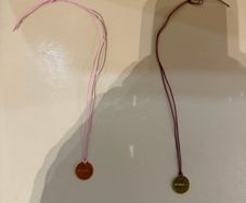 Rituals red/pink string bracelet with round Rituals engraved charm