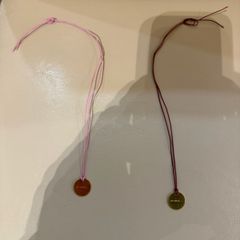 Rituals red/pink string bracelet with round Rituals engraved charm