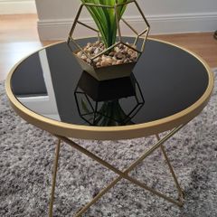 Round side table with black glass top and gold frame