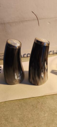 Set of 2 Buffalo Horn  Salt And Pepper Set topped with mother of pearl rimmed with sterling silver rim stamped.