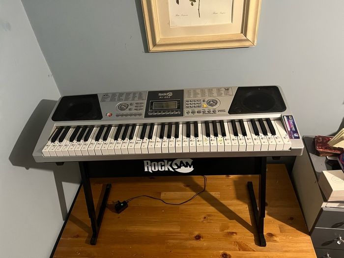 RockJam Electronic Keyboard Piano set up on a sturdy, matching heavy-duty Z-frame stand and an adjustable padded X-frame RockJam Keyboard Bench resting on a wooden surface.