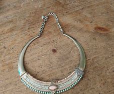 choker necklace. It combines a rigid metallic collar band with an intricately layered bohemian bib display.