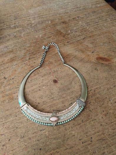 choker necklace. It combines a rigid metallic collar band with an intricately layered bohemian bib display.