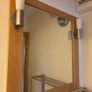 This pine-framed mirror includes two attached wall sconces for lighting. Image 2