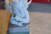 A small clay figure of an white angel on a marble plaint .