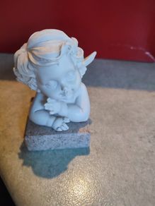 A small clay figure of an white angel on a marble plaint .