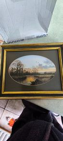 VINTAGE Framed landscape print featuring an oval matte aperture with a golden sunset or sunrise over a river, bare trees, and two birds flying in the sky.