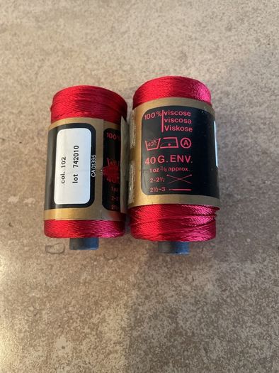 Two spools of red viscose knitting and crochet yarn
