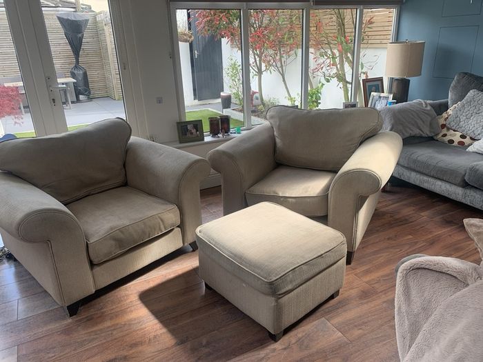 Two extra wide beige armchairs and pouffe