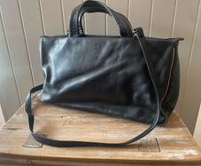 Tula black leather tote bag with a shoulder strap.
