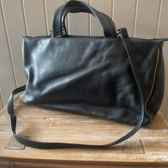 Tula black leather tote bag with a shoulder strap.
