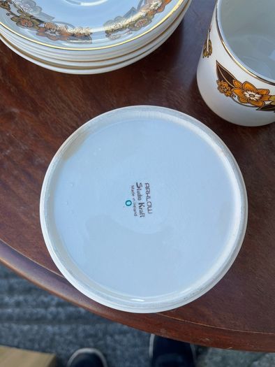 The set shown is a 1970s Arklow Pottery "Studio Kraft" tea/coffee set manufactured in County Wicklow, Ireland. It features a classic 1970s mid-century retro floral pattern in amber, orange, and brown tones with gold trim