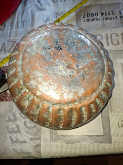 Antique Copper Cauldron features a Rustic Patina, a Swing Handle, and Distinctive Ribbed Detailing around the Rim. It resembles vintage metal pots often used for hearth decoration or as Planters. The piece shows significant oxidation and aging, characteri