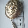A large medallion featuring religious symbols, suspended from a long chain. Image 6